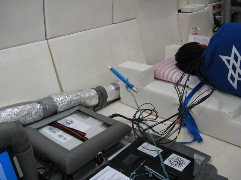 Close view of cabling and experimental equipment next to padded aircraft couch